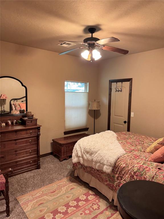 bedroom with a textured ceiling, light colored carpet, and ceiling fan