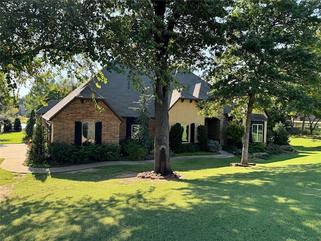 view of front of house with a front lawn, brick siding, and a shingled roof