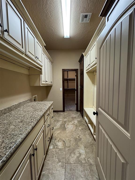 laundry room with visible vents, cabinet space, a textured ceiling, and washer hookup