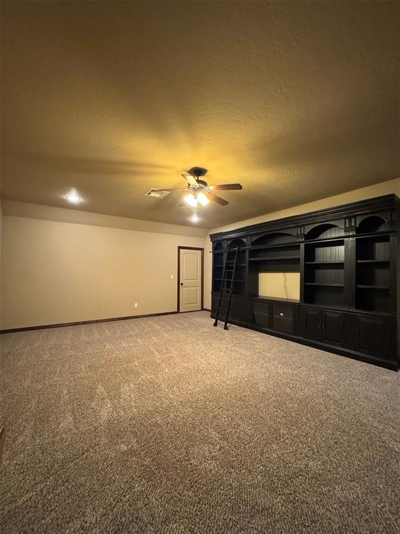 unfurnished living room featuring baseboards, a textured ceiling, ceiling fan, and carpet flooring