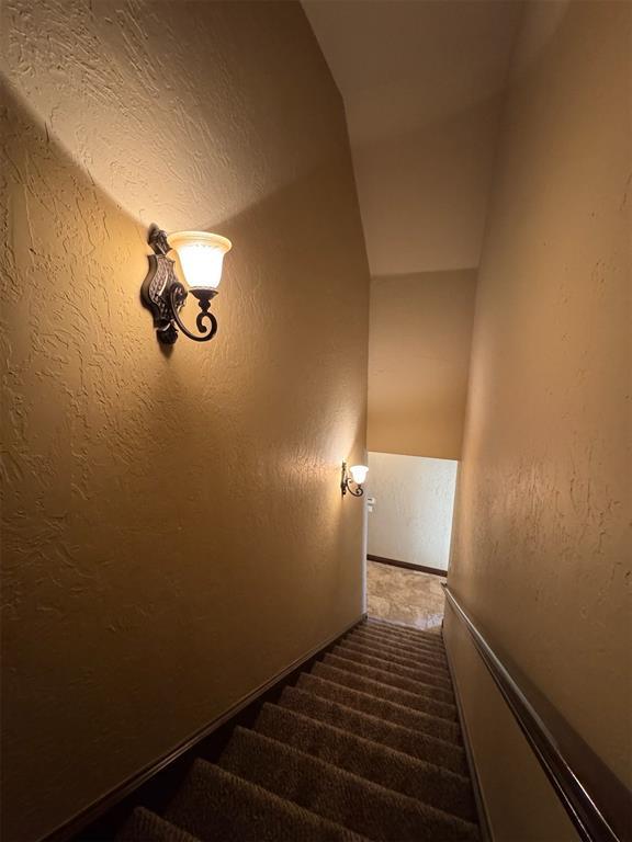 stairway featuring carpet flooring and a textured wall