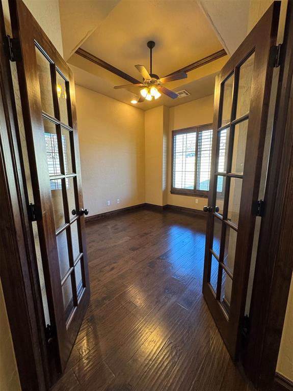 spare room featuring a tray ceiling, baseboards, dark wood-style floors, and french doors