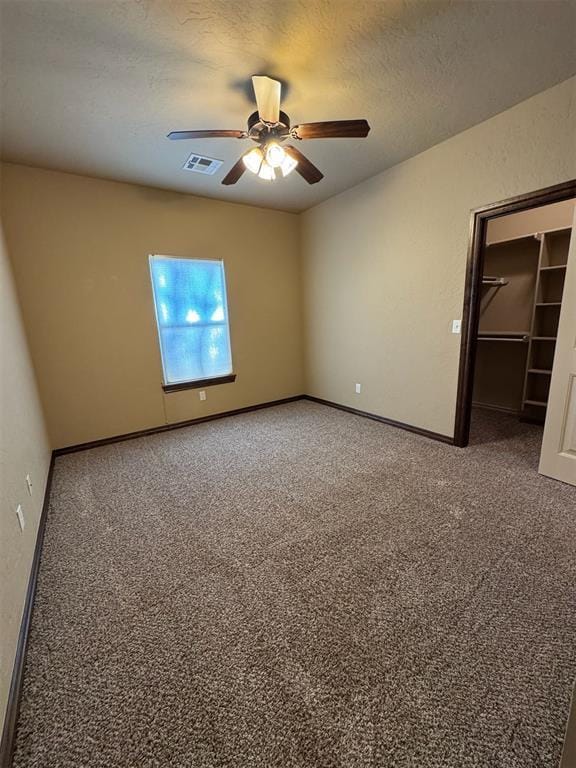 unfurnished bedroom with visible vents, carpet floors, a textured ceiling, and a spacious closet