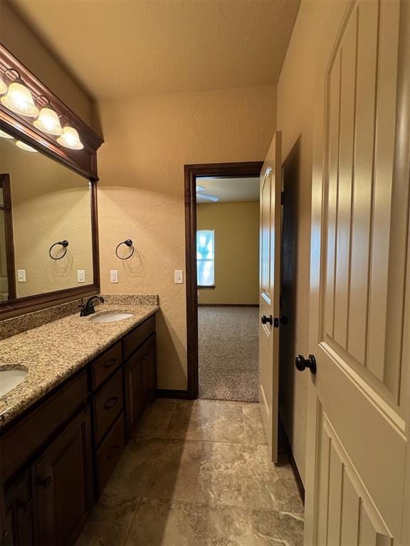 bathroom with a sink, double vanity, and a textured wall