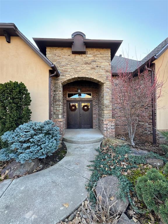 doorway to property featuring stone siding and stucco siding