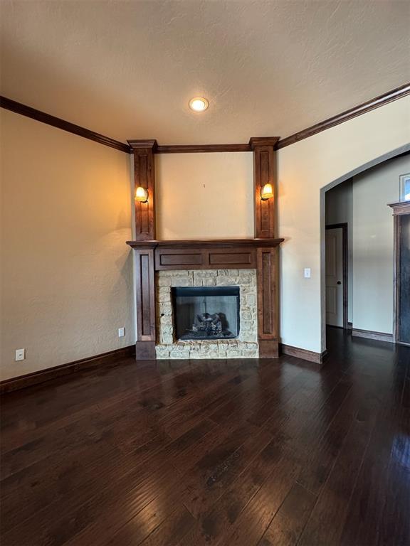 unfurnished living room featuring baseboards, hardwood / wood-style floors, a fireplace, and ornamental molding