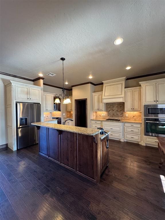 kitchen featuring light stone countertops, cream cabinets, appliances with stainless steel finishes, and dark wood finished floors