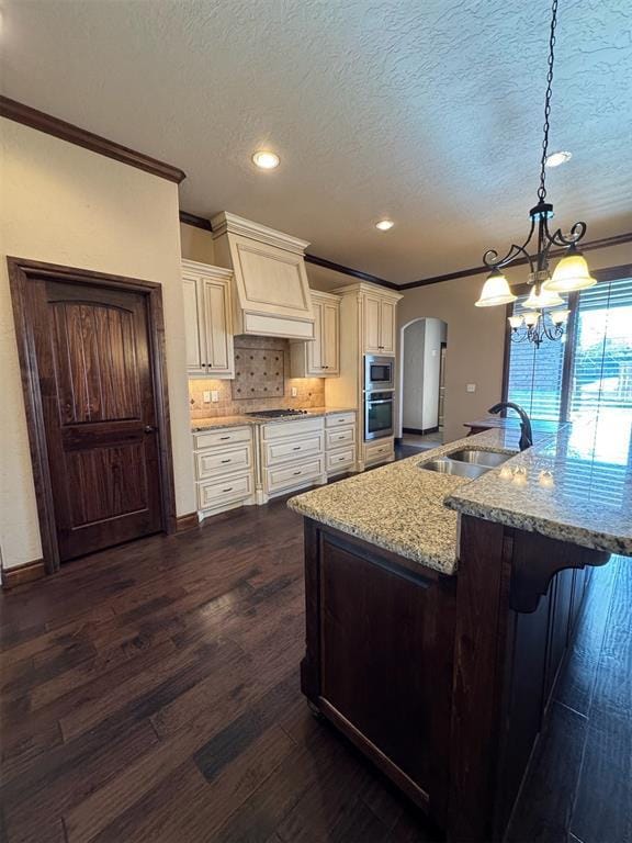 kitchen featuring a sink, arched walkways, appliances with stainless steel finishes, and ornamental molding