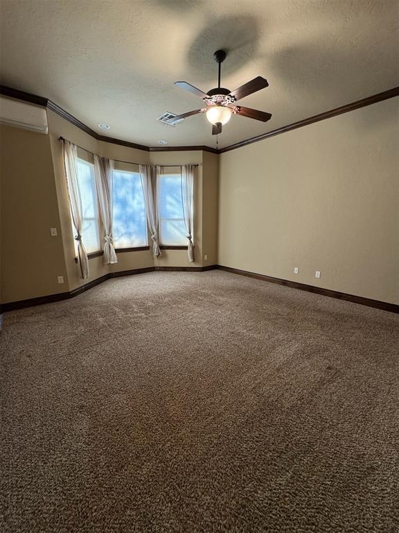 unfurnished room with a textured ceiling, light colored carpet, baseboards, and ornamental molding