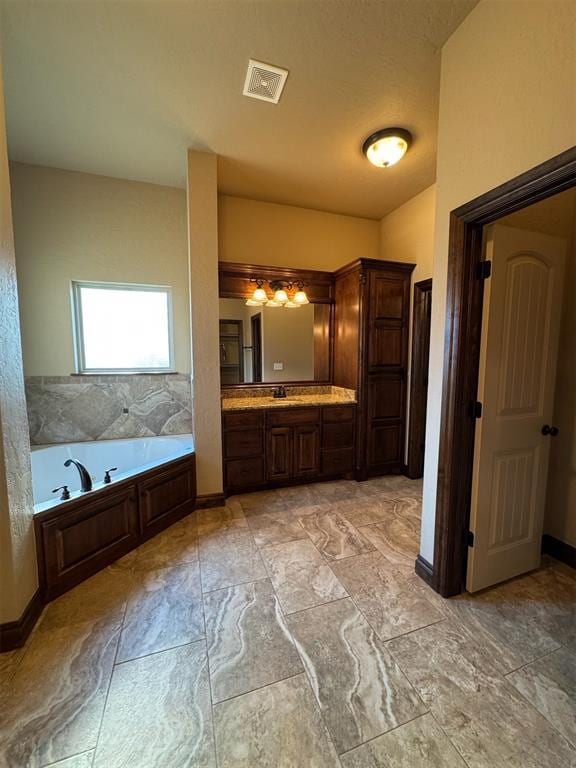 bathroom featuring a bath, visible vents, vanity, and baseboards