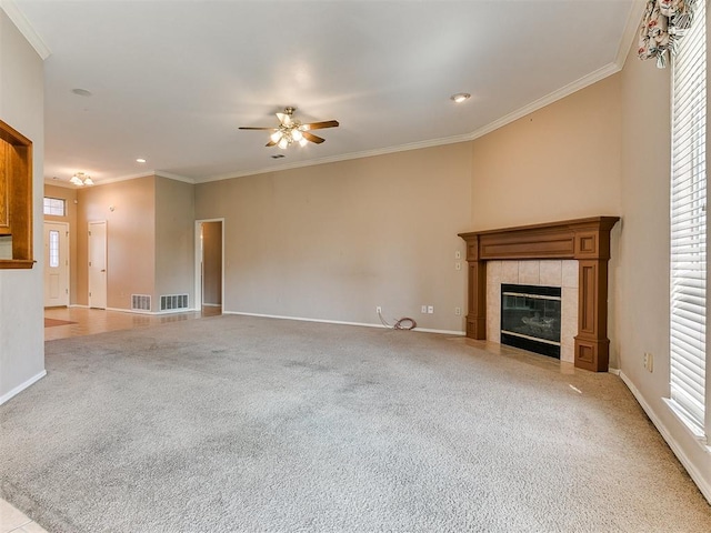 unfurnished living room featuring ceiling fan, plenty of natural light, crown molding, and a tiled fireplace