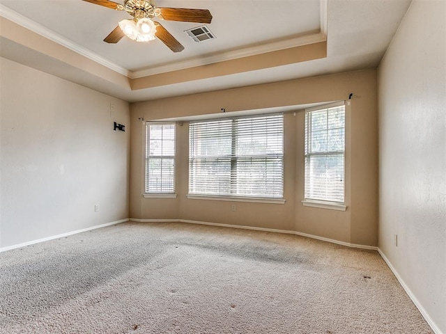 unfurnished room featuring carpet flooring, a raised ceiling, plenty of natural light, and ornamental molding