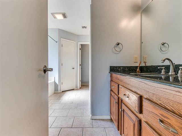 bathroom with a tub to relax in, tile patterned flooring, and vanity