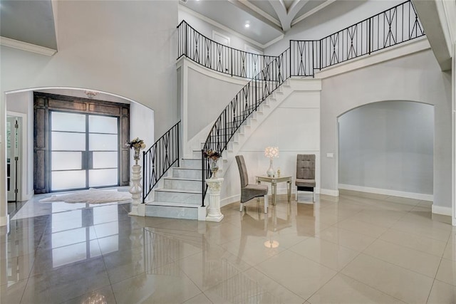 tiled foyer entrance featuring crown molding and a towering ceiling