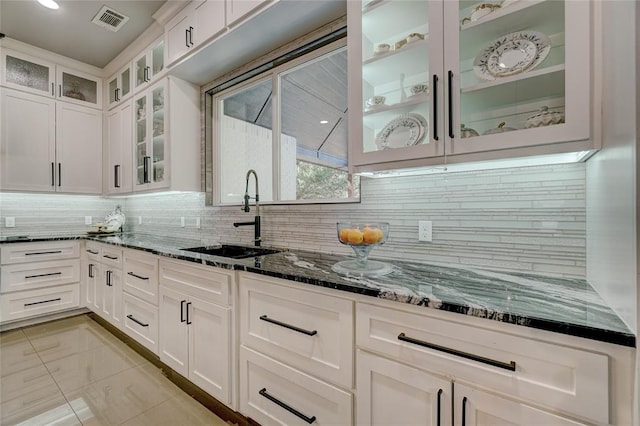 kitchen featuring backsplash, white cabinetry, sink, and dark stone counters