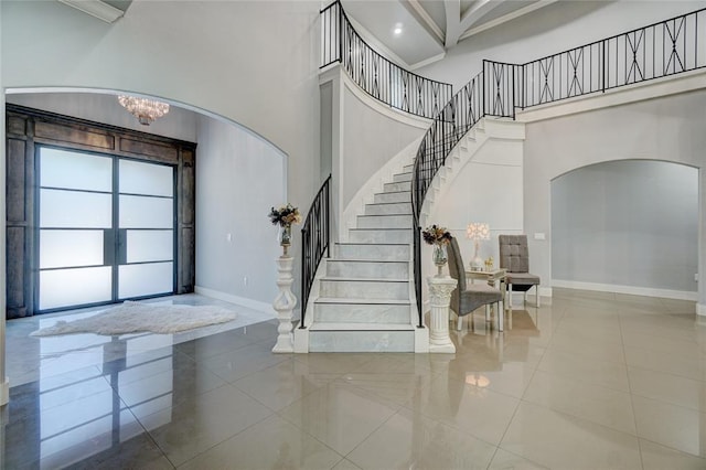 tiled entryway with a high ceiling and a chandelier