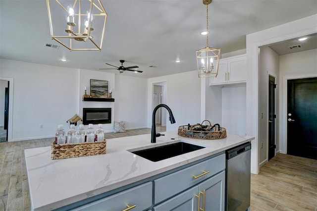 kitchen with light stone counters, hanging light fixtures, white cabinetry, and stainless steel dishwasher