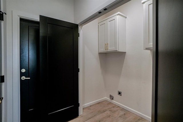 clothes washing area with cabinets, light hardwood / wood-style flooring, and electric dryer hookup