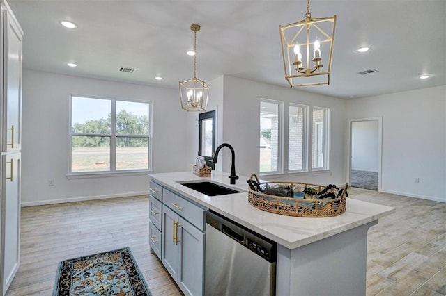 kitchen featuring hanging light fixtures, stainless steel dishwasher, sink, and a center island with sink