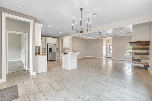 kitchen with pendant lighting, stainless steel fridge, white cabinetry, and a tray ceiling