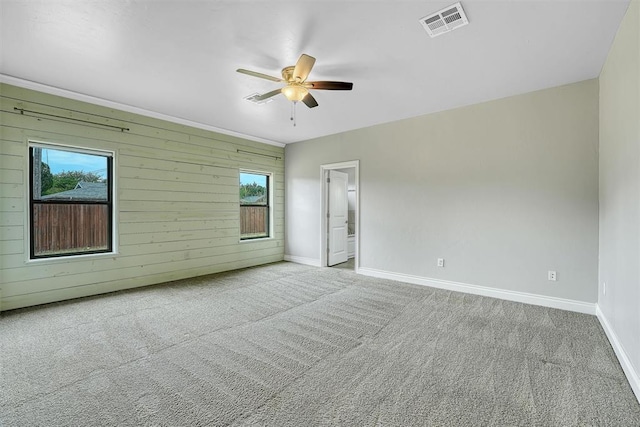 empty room featuring a wealth of natural light, wooden walls, and light carpet