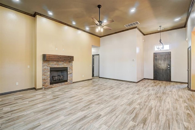 unfurnished living room featuring ceiling fan, a stone fireplace, ornamental molding, and light hardwood / wood-style flooring