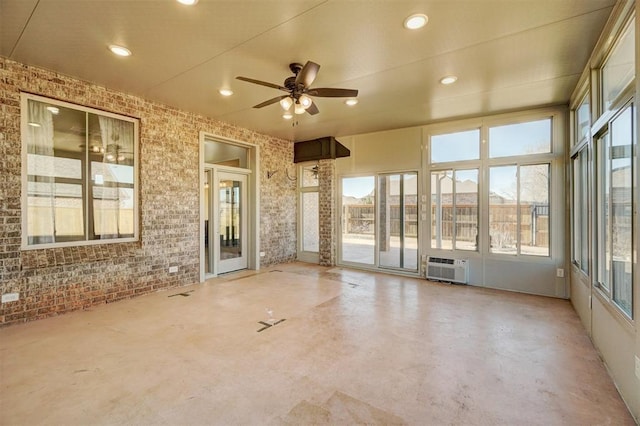 unfurnished sunroom with an AC wall unit and ceiling fan