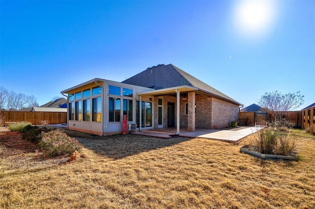 rear view of house with a lawn, a patio area, and a sunroom