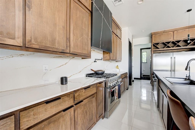 kitchen featuring light stone counters, sink, pendant lighting, range with two ovens, and light tile patterned flooring