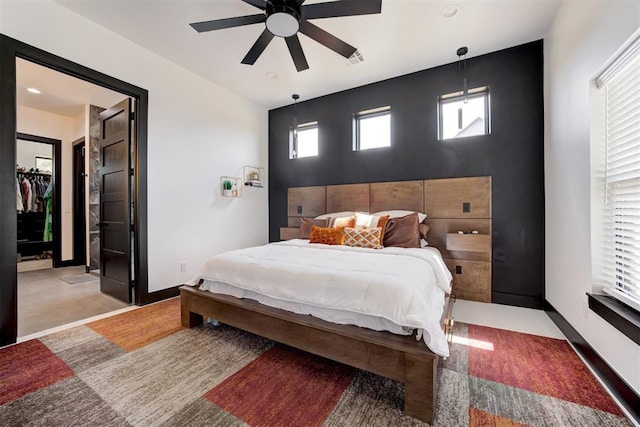 bedroom featuring a walk in closet, a closet, and ceiling fan