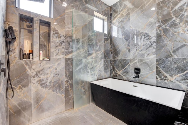 bathroom featuring plus walk in shower, tile walls, and a wealth of natural light