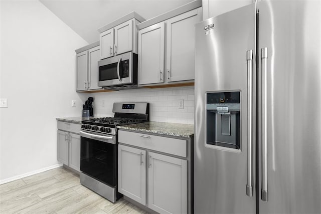 kitchen featuring appliances with stainless steel finishes, decorative backsplash, light stone counters, and gray cabinetry