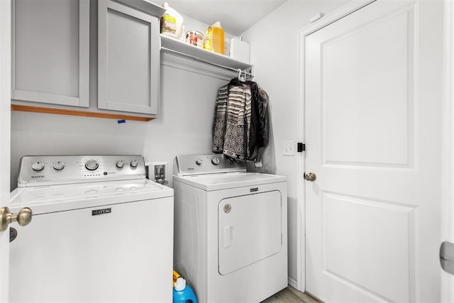 clothes washing area featuring cabinet space and independent washer and dryer