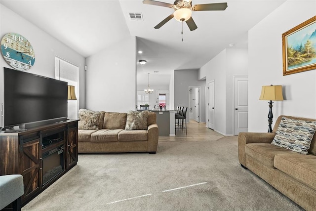 living area with visible vents, vaulted ceiling, light carpet, and ceiling fan with notable chandelier