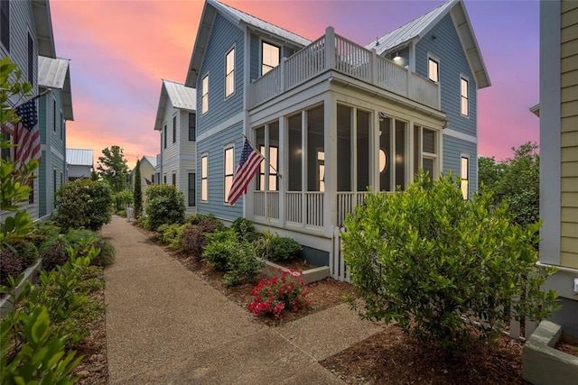 property exterior at dusk featuring a sunroom and a balcony