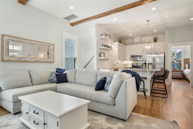 living room with light hardwood / wood-style flooring and beamed ceiling