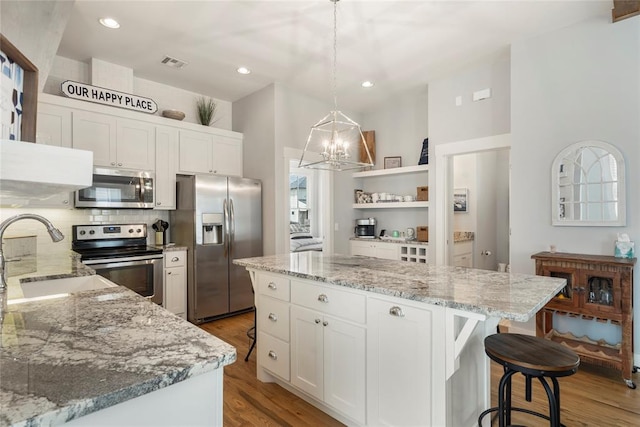 kitchen featuring pendant lighting, white cabinets, sink, appliances with stainless steel finishes, and a kitchen island