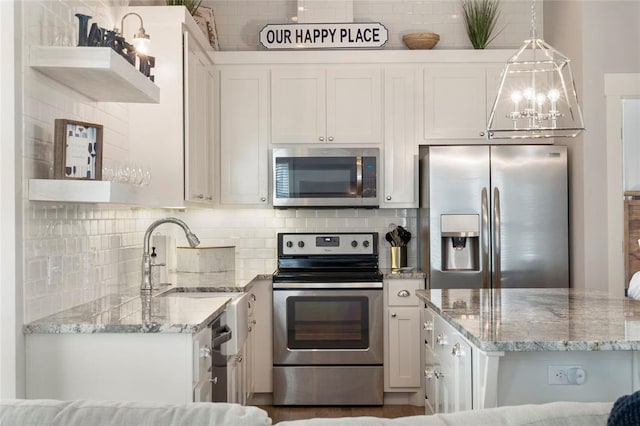 kitchen with light stone counters, stainless steel appliances, sink, white cabinetry, and hanging light fixtures