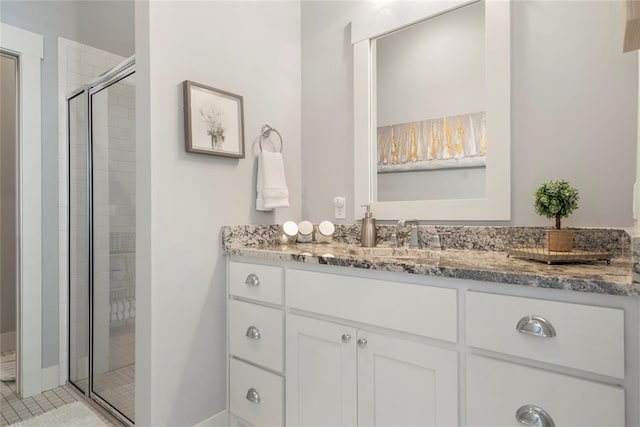 bathroom with a shower with door, vanity, and tile patterned flooring