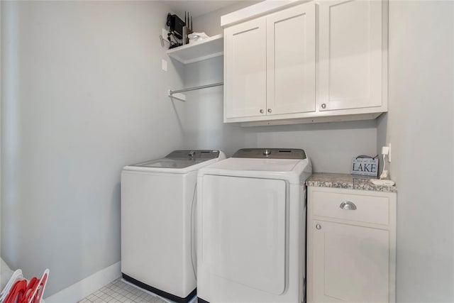 washroom featuring washing machine and clothes dryer, light tile patterned flooring, and cabinets