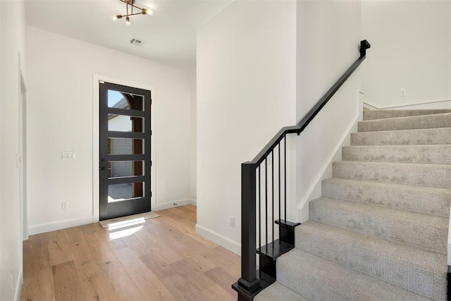 foyer entrance featuring stairway, wood finished floors, visible vents, and baseboards