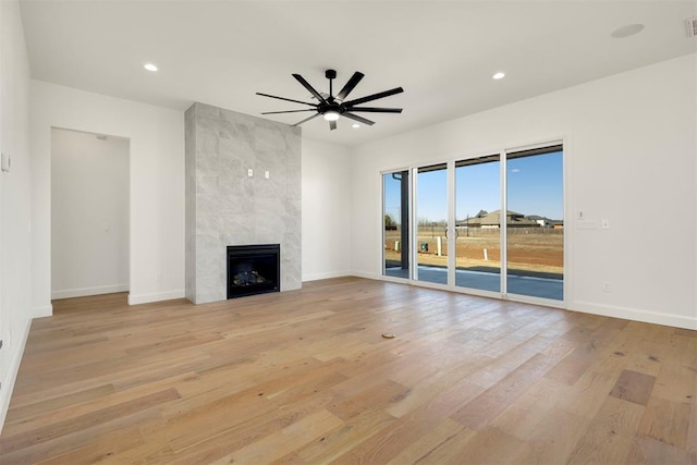 unfurnished living room featuring a ceiling fan, recessed lighting, a fireplace, light wood finished floors, and baseboards