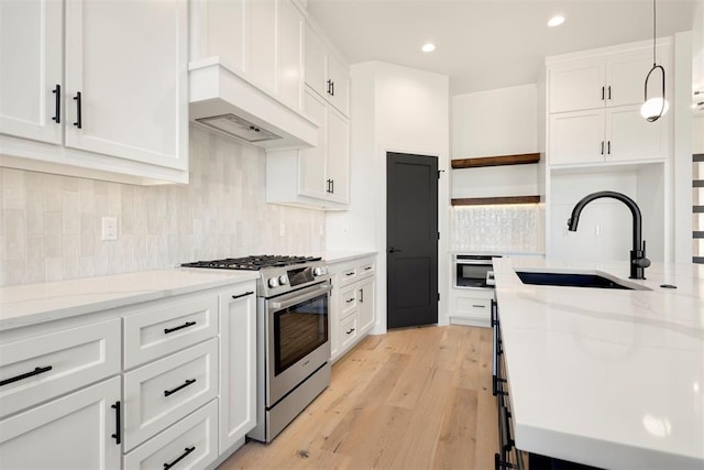 kitchen with open shelves, white cabinets, appliances with stainless steel finishes, and a sink