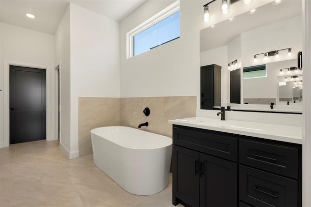 full bath with a soaking tub, tile walls, and vanity