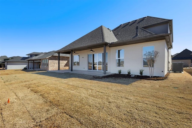 back of property with a patio, a ceiling fan, a yard, central AC, and a shingled roof