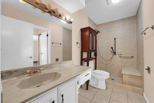 bathroom with a tile shower, tile patterned floors, a textured ceiling, toilet, and vanity