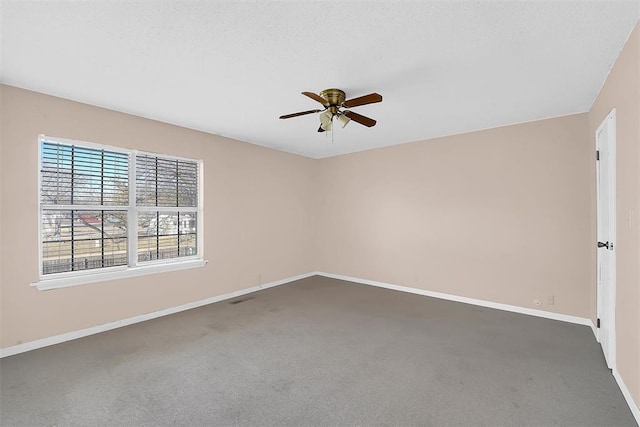 spare room featuring ceiling fan, dark carpet, and a textured ceiling