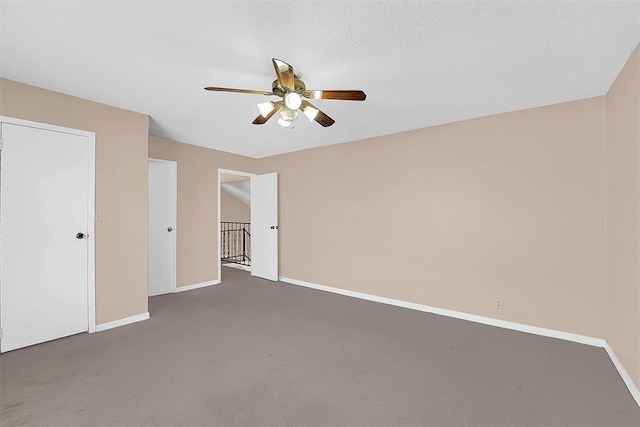 unfurnished bedroom with ceiling fan, dark carpet, and a textured ceiling