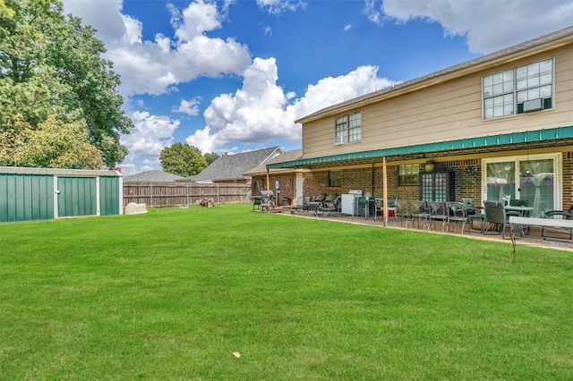 rear view of property with a lawn, a patio, and a storage unit