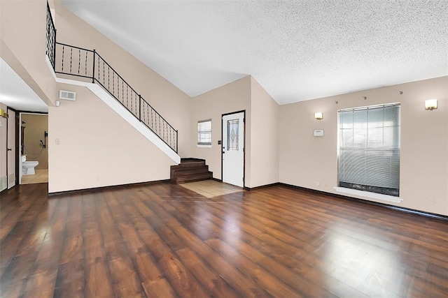 interior space with a towering ceiling, a textured ceiling, and dark hardwood / wood-style floors